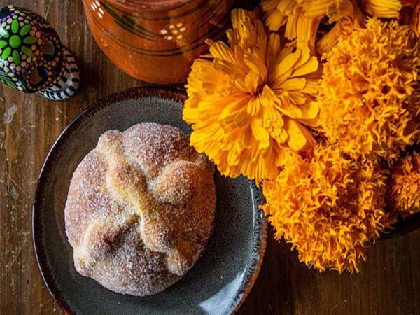 Pan de muerto con flor de cempasúchil, mole y hoja santa